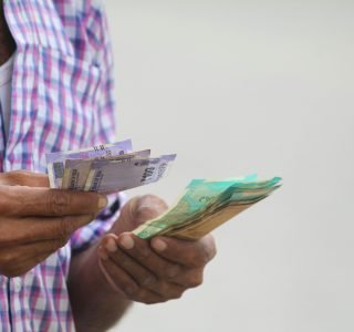 A person counts colorful banknotes, showcasing a financial transaction in detail.