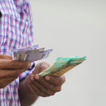 A person counts colorful banknotes, showcasing a financial transaction in detail.
