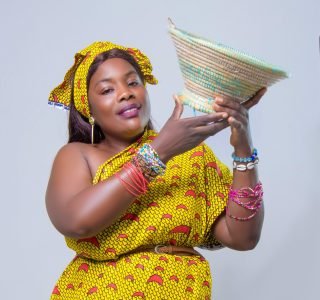 Colorful portrait of an African woman in traditional attire holding a woven basket.