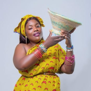 Colorful portrait of an African woman in traditional attire holding a woven basket.