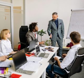 Corporate team in a modern office, engaged in a discussion with diverse colleagues.